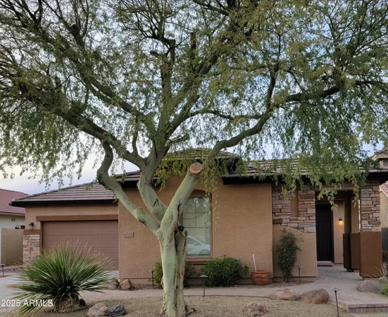 a front view of a house with a tree