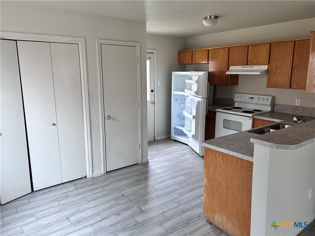 4103 Wine Cup, Unit C Copperas Cove, TX 76522 - Photo 3 of 8 a kitchen with a refrigerator a stove top oven a sink and dishwasher with wooden floor