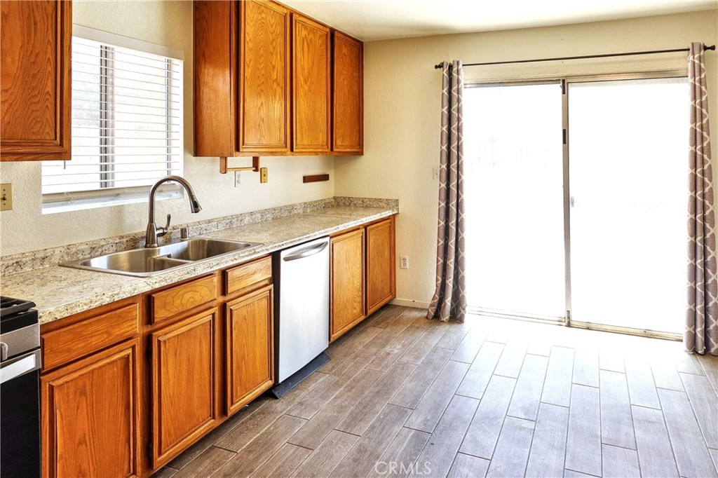 10403 Buckboard Circle Adelanto, CA 92301 - Photo 2 of 20 a kitchen with stainless steel appliances granite countertop a sink and a wooden cabinets
