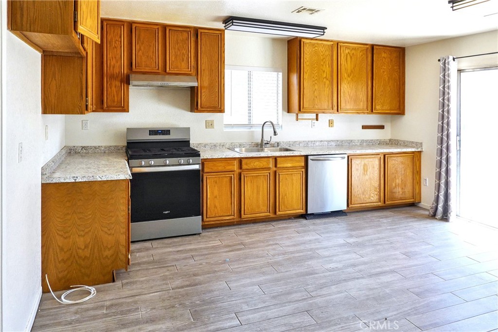 10403 Buckboard Circle Adelanto, CA 92301 - Photo 3 of 20 a kitchen with stainless steel appliances granite countertop a sink stove and refrigerator