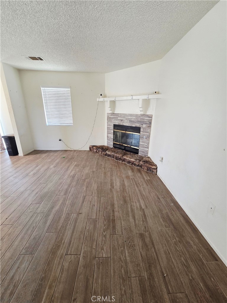 10403 Buckboard Circle Adelanto, CA 92301 - Photo 7 of 20 a view of empty room with wooden floor and fireplace