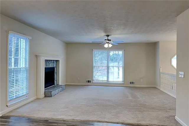 an empty room with chandelier fan and windows
