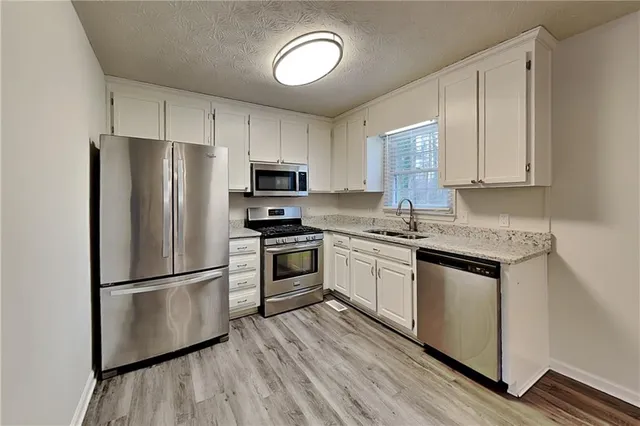 a kitchen with granite countertop stainless steel appliances a refrigerator cabinets and wooden floor