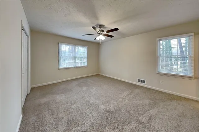 an empty room with windows and ceiling fan