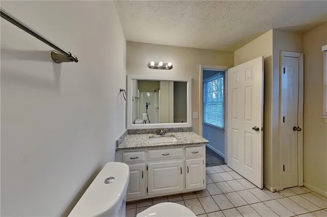 a bathroom with a granite countertop sink mirror and toilet