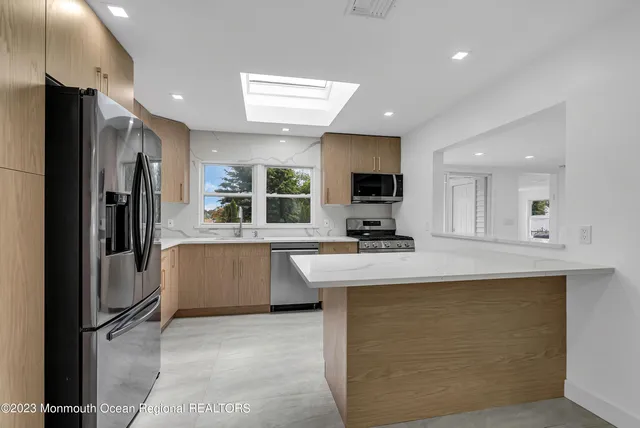 a large kitchen with kitchen island a sink a counter top stainless steel appliances and cabinets