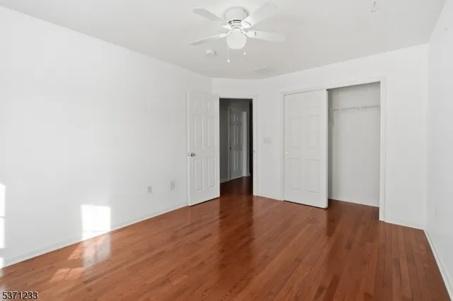 an empty room with wooden floor and a ceiling fan