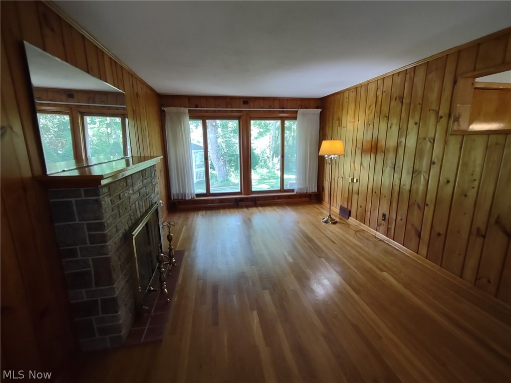 595 Barrett Road Berea, OH 44017 - Photo 2 of 18 living room with a brick fireplace, wood walls, and hardwood / wood-style floors