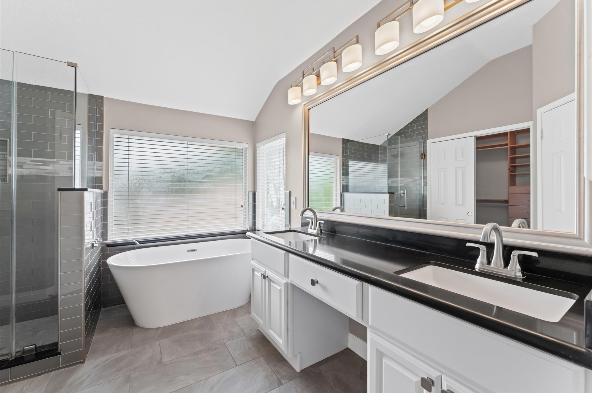 9202 State Walk Circle Houston, TX 77064 - Photo 12 of 25 This bathroom features a modern design with a sleek double vanity, large mirror, and stylish lighting. It includes a freestanding tub and a glass-enclosed shower