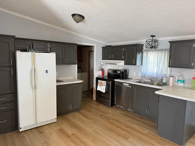 a kitchen with a refrigerator a sink and dishwasher with wooden floor