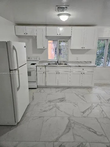 a kitchen with white cabinets and white appliances