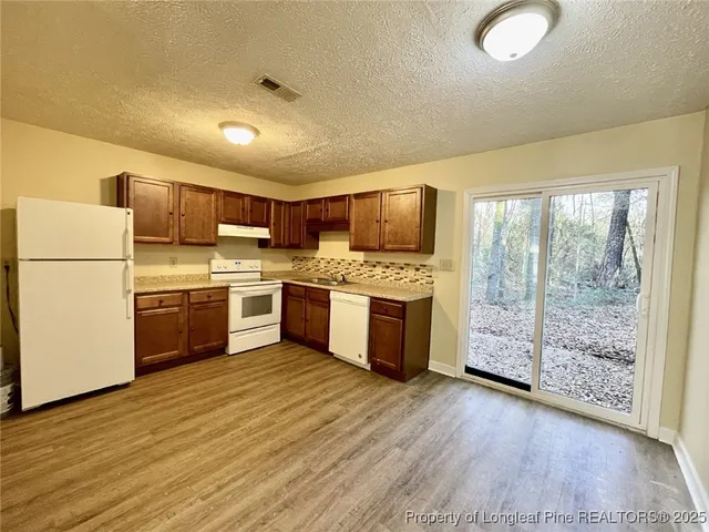 a kitchen with granite countertop a stove a sink dishwasher a refrigerator and cabinets with wooden floor