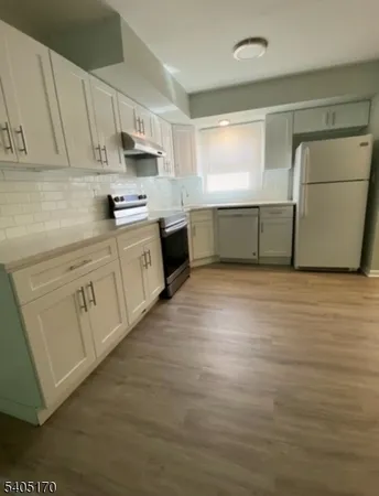 a kitchen with stainless steel appliances granite countertop a stove a sink and white cabinets