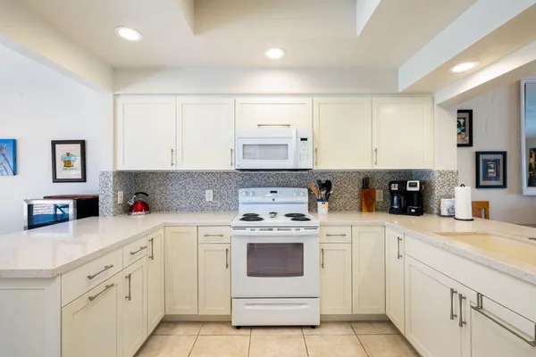 a kitchen with white cabinets and white appliances