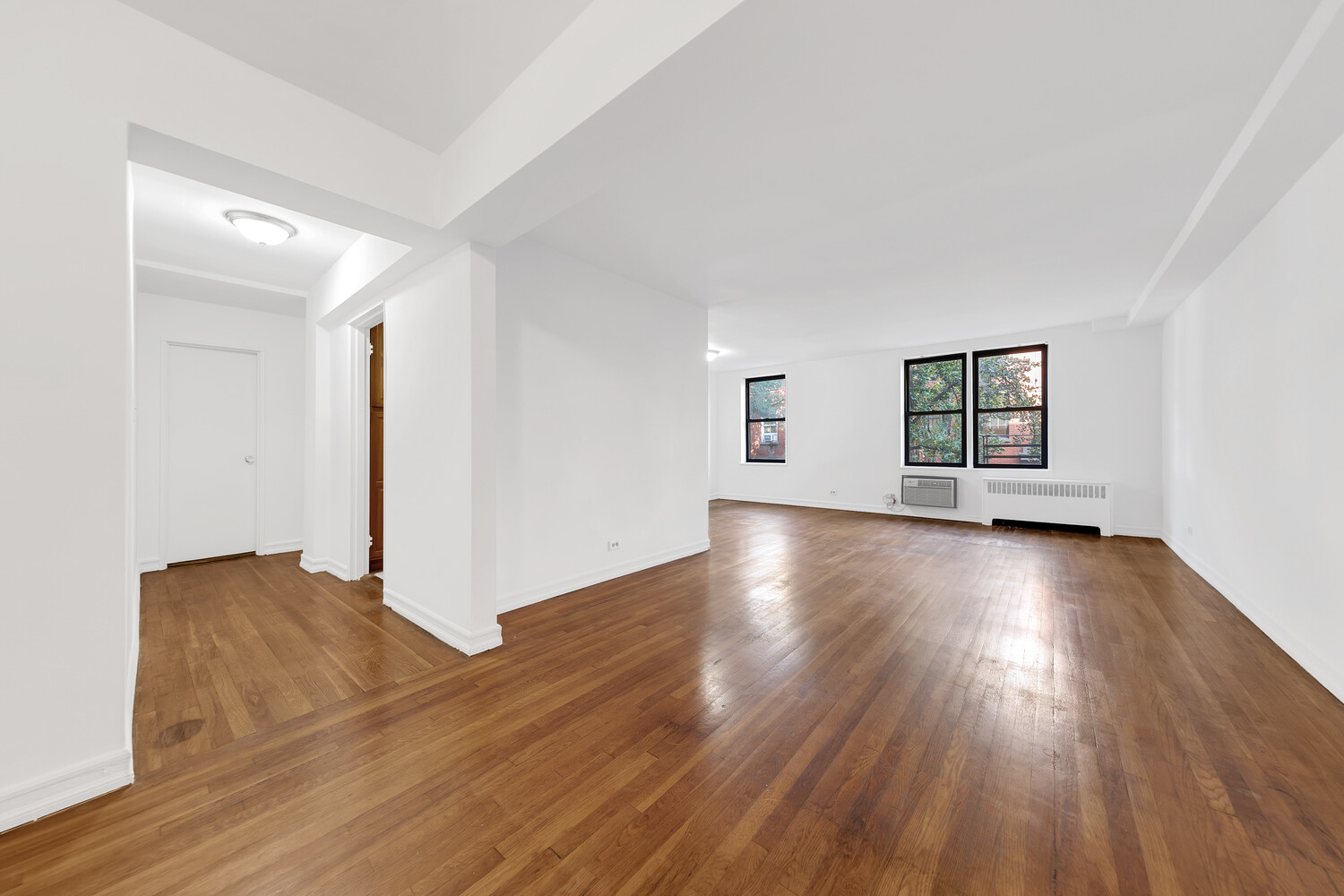 100 Bank Street, Unit 2B Manhattan, NY 10014 - Photo 2 of 9 an empty room with wooden floor and windows