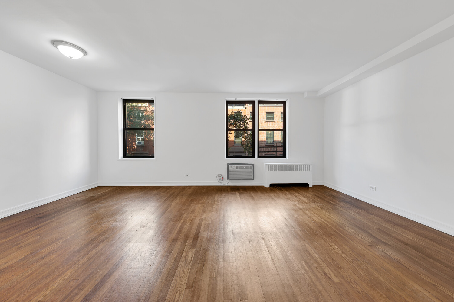 100 Bank Street, Unit 2B Manhattan, NY 10014 - Photo 3 of 9 an empty room with wooden floor and windows
