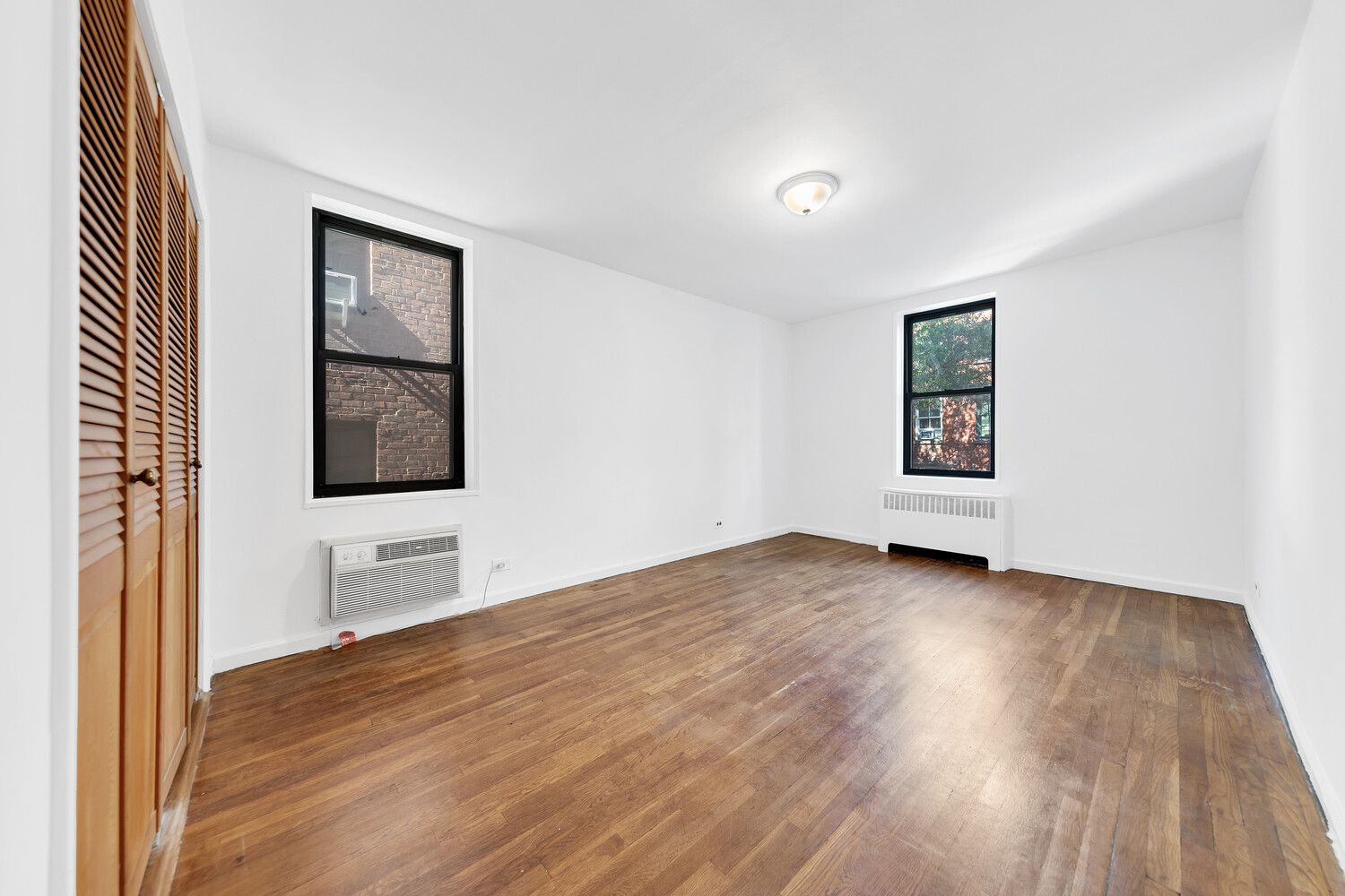 100 Bank Street, Unit 2B Manhattan, NY 10014 - Photo 6 of 9 an empty room with wooden floor and windows