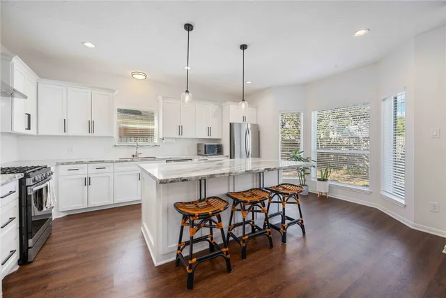 a kitchen with stainless steel appliances a table chairs sink and cabinets