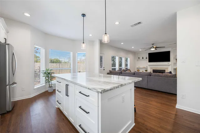 a large kitchen with stainless steel appliances kitchen island granite countertop a large center island a sink a stove and a wooden floor