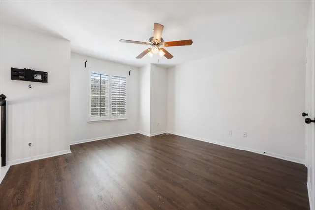 an empty room with wooden floor chandelier fan and windows