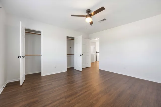 an empty room with wooden floor and ceiling fan