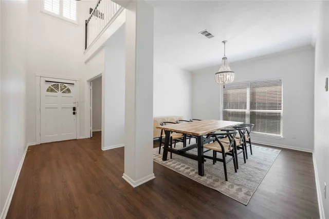 a dining room with wooden floor a chandelier a wooden table and chairs