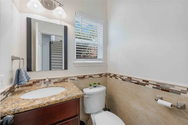 a bathroom with a granite countertop sink a mirror and a toilet