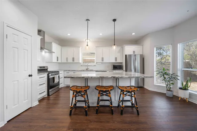 a kitchen with stainless steel appliances granite countertop a table chairs stove a sink dishwasher and cabinets with wooden floor