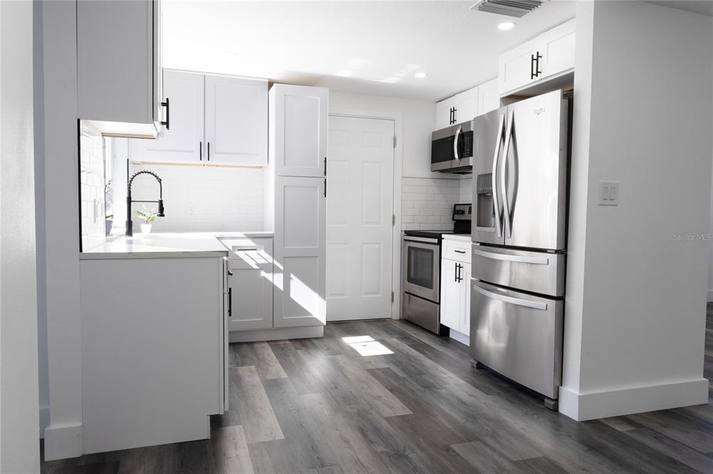 6340 Westport Drive Port Richey, FL 34668 - Photo 16 of 51 a kitchen with stainless steel appliances a refrigerator sink and cabinets