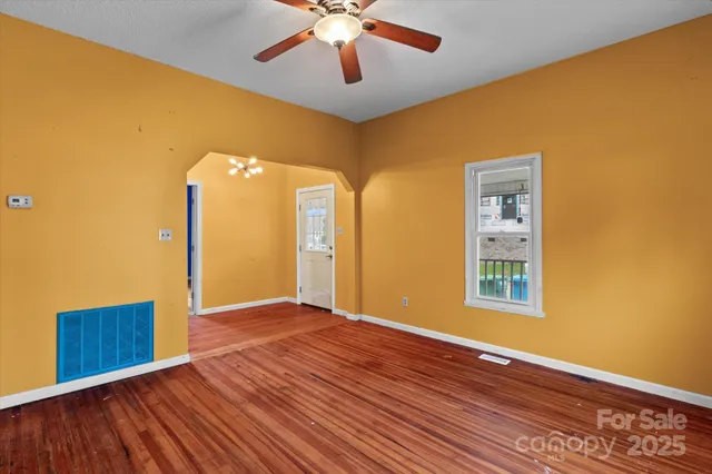 a view of an empty room with window and wooden floor