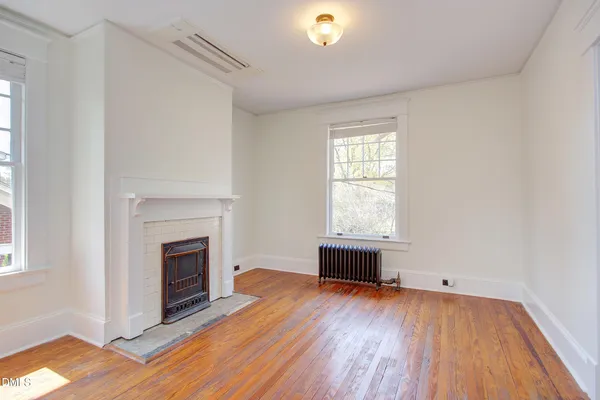 a view of empty room with wooden floor and fireplace