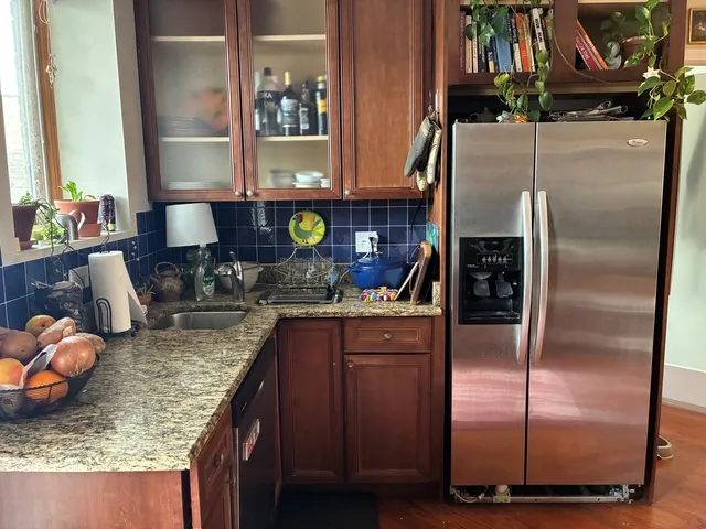 a kitchen with a refrigerator a stove and a sink with wooden floor