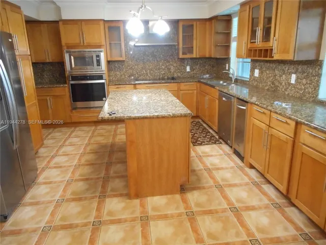 a kitchen with granite countertop a stove a sink and a microwave