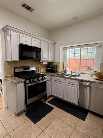 a large kitchen with granite countertop a stove a sink and a microwave