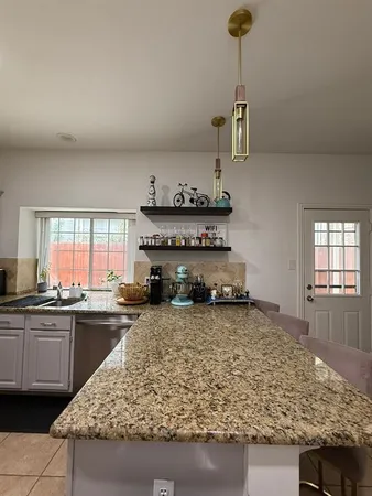 a kitchen with kitchen island granite countertop a sink a counter top space and cabinets