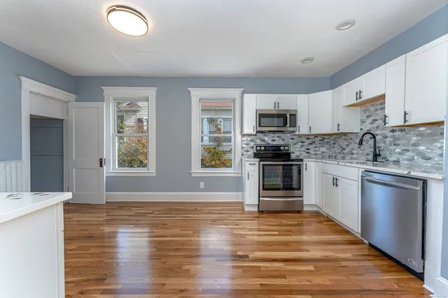 a kitchen with granite countertop a stove top oven a sink dishwasher and a refrigerator with wooden floor