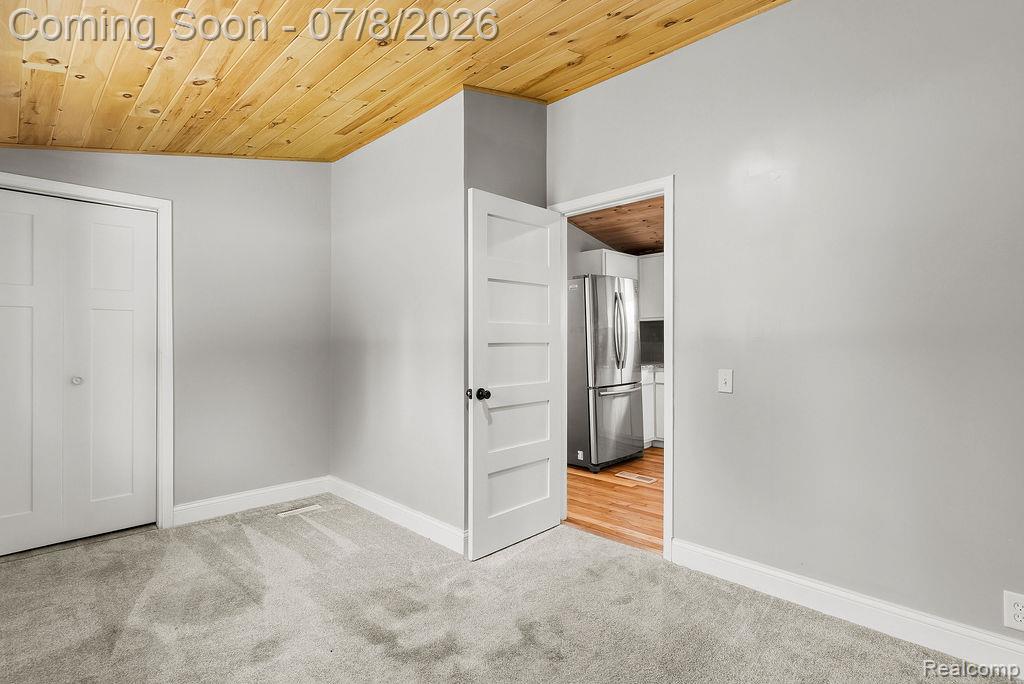 5698 McGrandy Road Bridgeport, MI 48722 - Photo 19 of 26 Interior room featuring a wood-panel ceiling, light gray wall paint, and gray carpet flooring