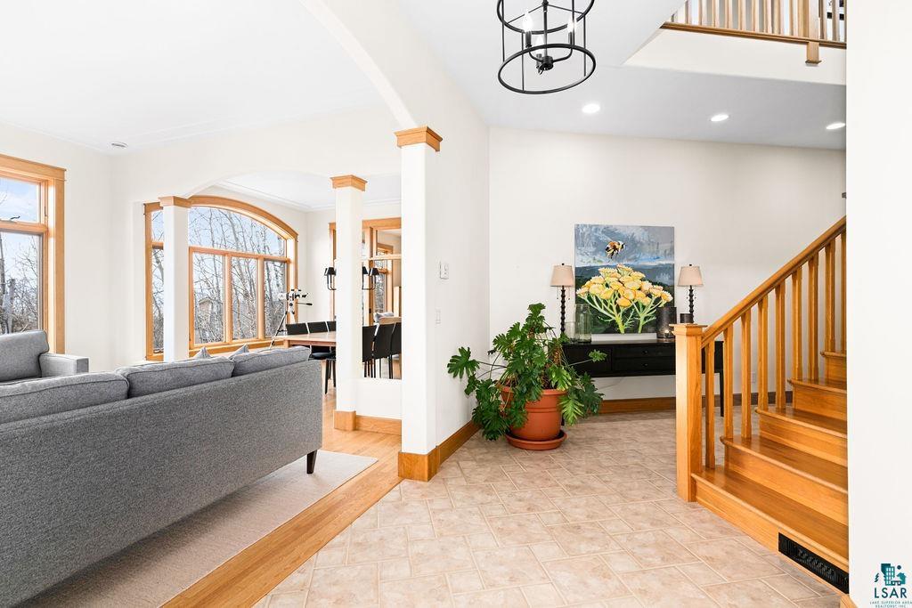 4856 Kingston Street Duluth, MN 55804 - Photo 22 of 88 Entry foyer featuring light-toned tile flooring, a natural wood staircase with balusters, and a black open-cage chandelier