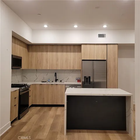 a kitchen with a sink and a stove top oven with wooden floor