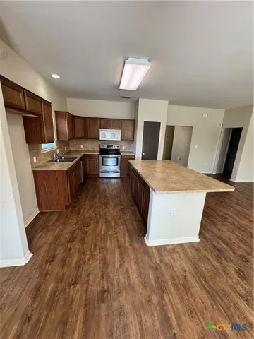 a living room with stainless steel appliances furniture and a kitchen view