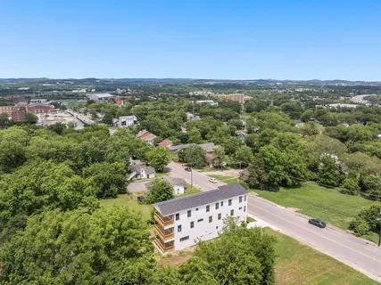 an aerial view of residential houses with outdoor space and trees