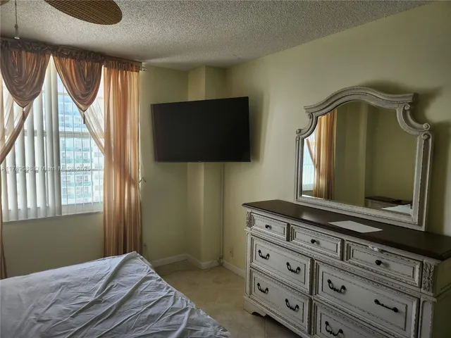 a bedroom with a bed and a flat tv screen on dresser