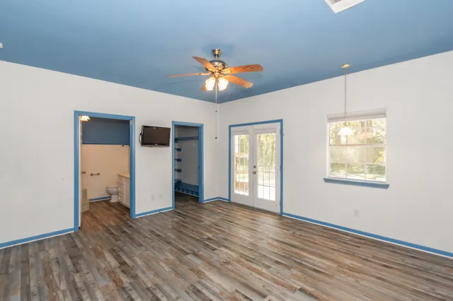 a view of an empty room with window and wooden floor