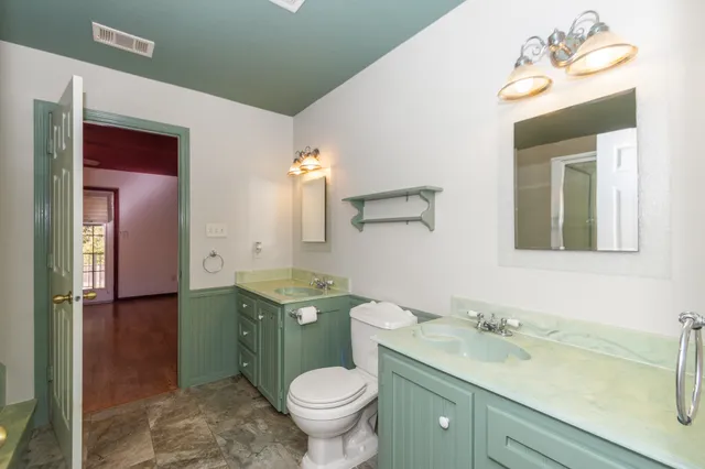 a bathroom with a granite countertop toilet sink and mirror