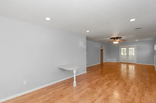 a view of an empty room with window and wooden floor