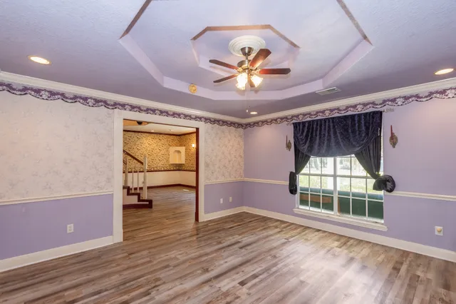a view of empty room with wooden floor and fan