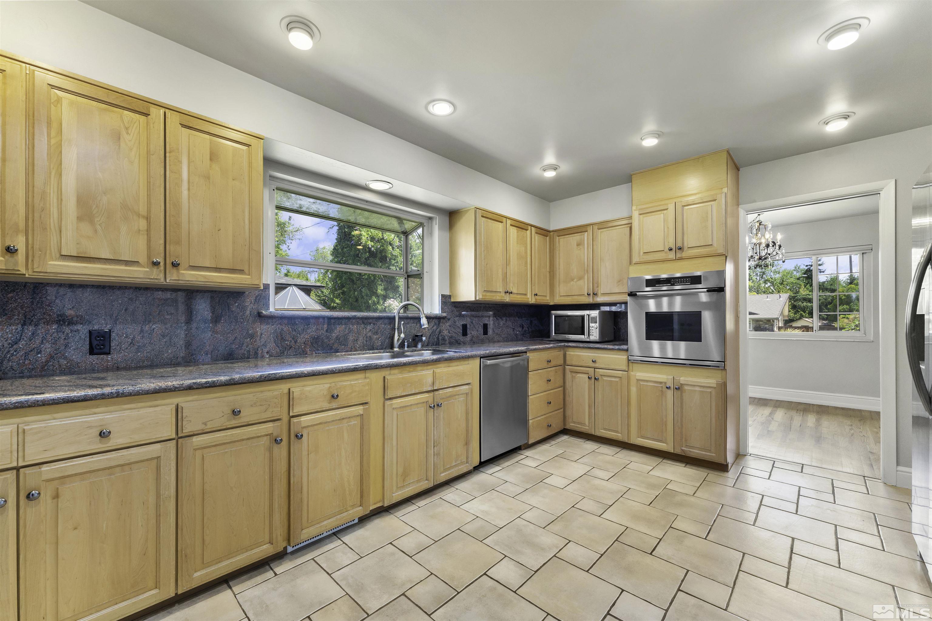 1401 Romero Way Reno, NV 89509 - Photo 14 of 28 a large kitchen with kitchen island granite countertop a large window and white cabinets