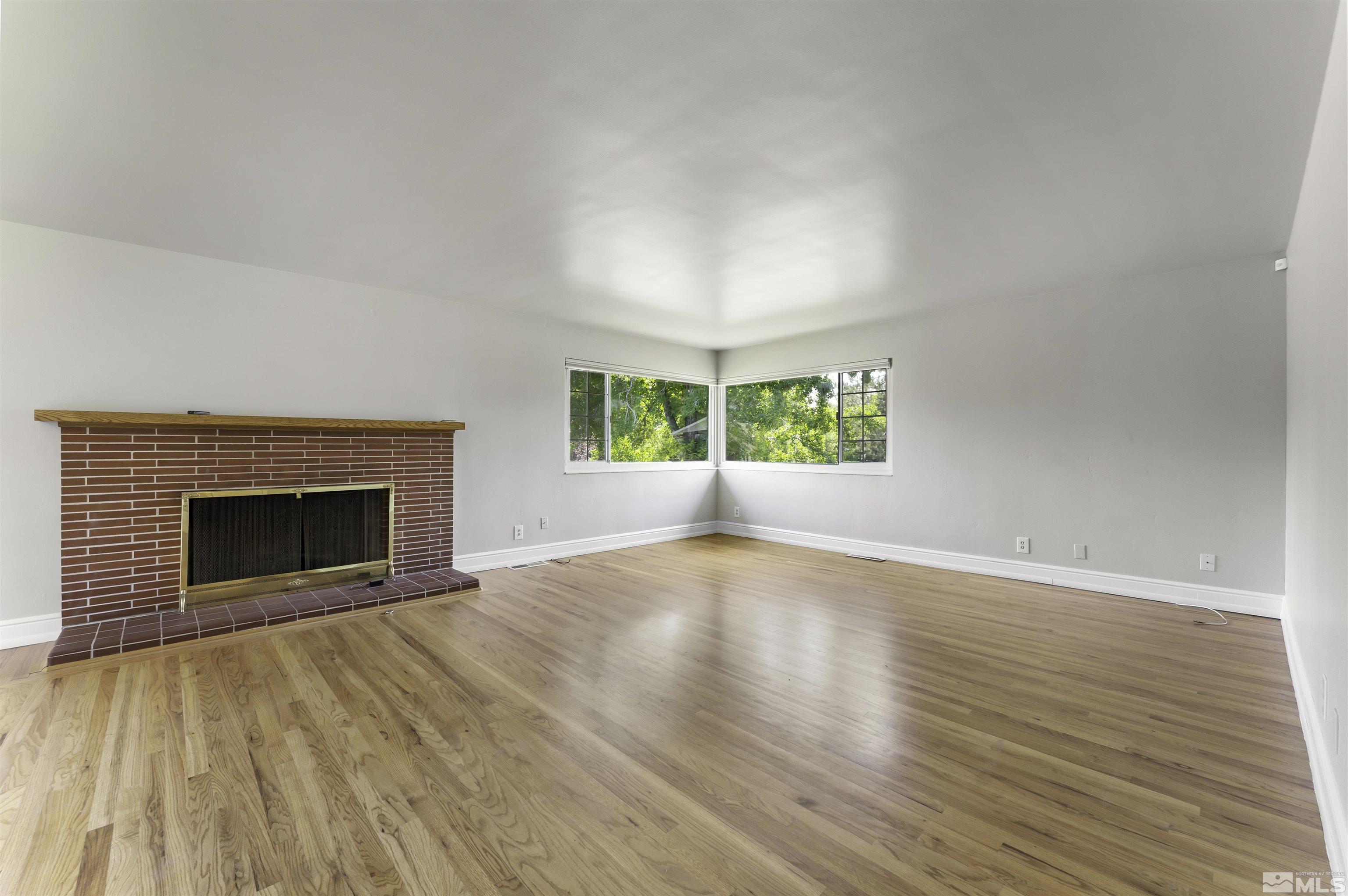 1401 Romero Way Reno, NV 89509 - Photo 7 of 28 an empty room with wooden floor a fireplace and windows