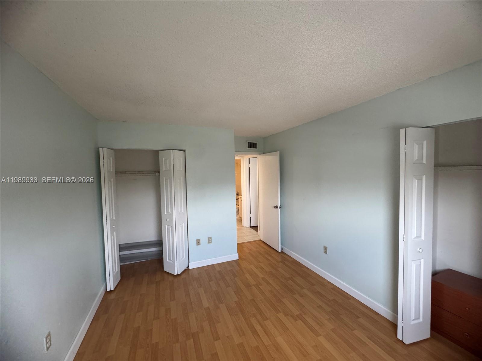 8075 Northwest 7th Street, Unit 403 Miami, FL 33126 - Photo 3 of 29 an empty room with wooden floor and closet