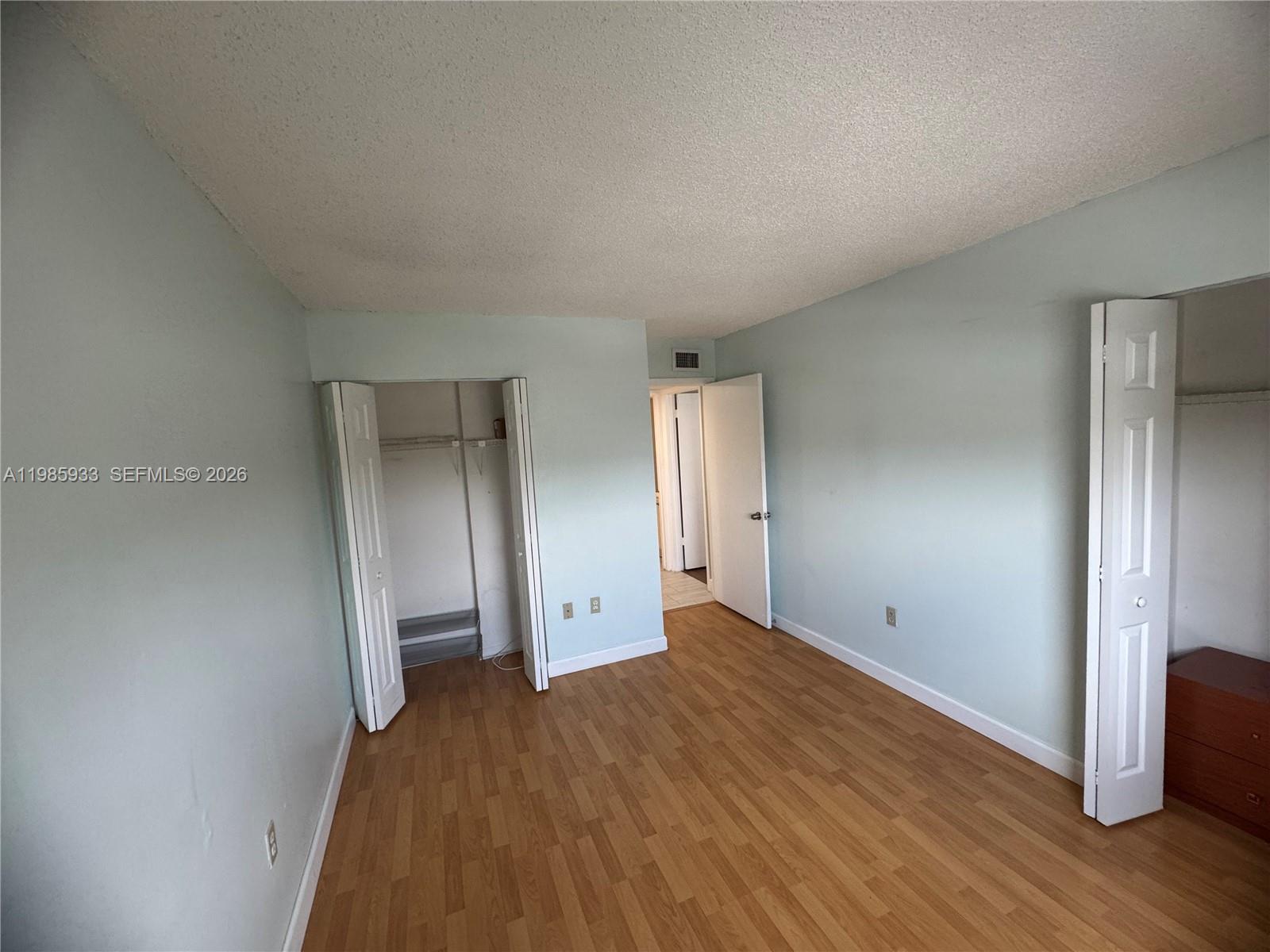 8075 Northwest 7th Street, Unit 403 Miami, FL 33126 - Photo 4 of 29 a view of an empty room with wooden floor and closet